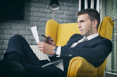 Businessman focused, reading document, working in homeの写真素材