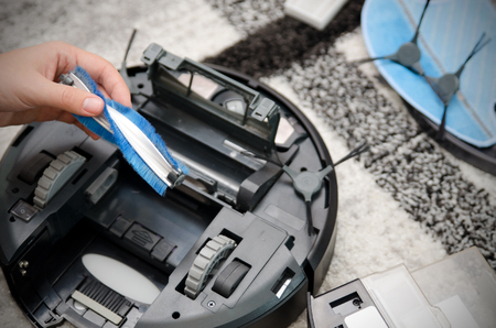 Robotic vacuum cleaner. Brush cleaning. Maintenance concept.の写真素材