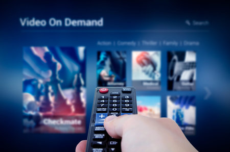 VOD service screen with remote control in hand. Video On Demand television internet stream...