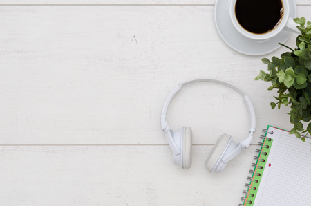 Office desk table with headphones, coffee cup and supplies. Flat lay with copy space on white wooden background.の写真素材