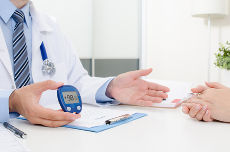 Doctor shows glucometer with glucose level. Doctor and patient diabetes consultation in office or clinic.の写真素材