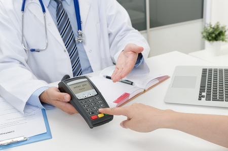 Payment for private medical care. Pos terminal at doctor officeの写真素材