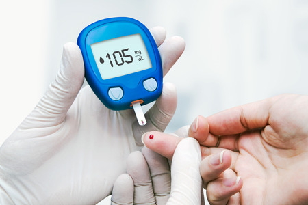 Doctor making blood sugar test in clinic for diabetes. Drop of blood on the fingerの写真素材