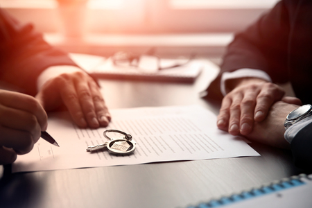 Real estate agent signing a contract buy-sell house. Two men sitting at the desk, home insurance policy on home loans, insurance agent conceptの写真素材