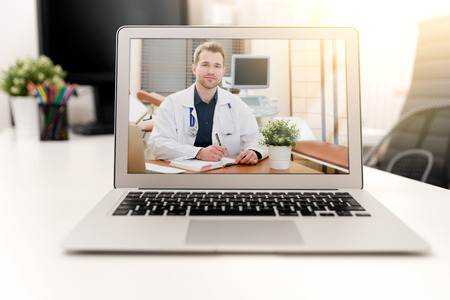 Doctor with a stethoscope on the computer laptop screen. Telemedicine or telehealth concept.の写真素材