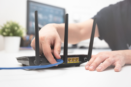 Man connects the internet cable to the router's socket. Fast and wireless internet conceptの写真素材