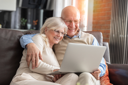 Senior couple browsing the internet together. Retirees using a laptop computer at homeの写真素材