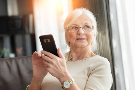 Portrait of elegant senior woman with smart phone. Lifestyle photo of pension woman.の写真素材