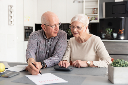 Senior couple discussing investment, checking their bills at homeの写真素材
