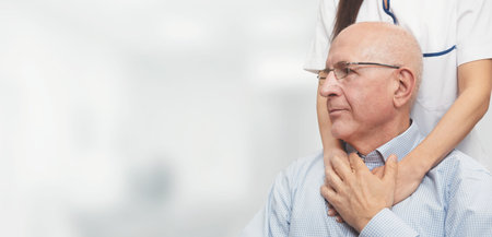 Health visitor and a senior man during home visit. Happy patient is holding caregiver for a hand...