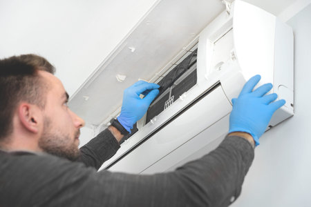 Technician repairing air conditioner appliance. Young man takes care of the cleanliness of the...