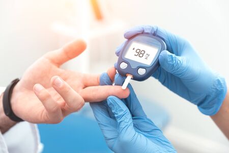 Doctor checking blood sugar level with glucometer. Treatment of diabetes concept.の写真素材