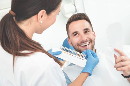 Handsome young man in stomatology clinic with female dentist. Healthy teeth whitening.の写真素材