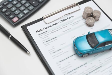 Motor or car insurance claim form with coin stack, calculator and car model.の写真素材