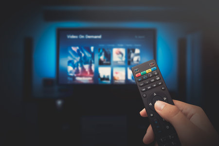 VOD service screen. Man watching TV with remote control in hand.