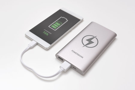 USB charger plugged in to smart phone. Power bank, mobile phone battery on desk concept