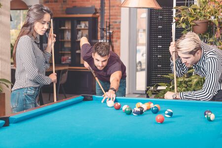 Group of employees playing in billiards at office. Break from work in the relaxation roomの写真素材