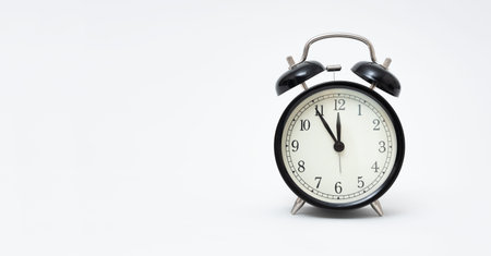 Retro alarm clock with five minutes to twelve o'clock. Clock isolated on white background.