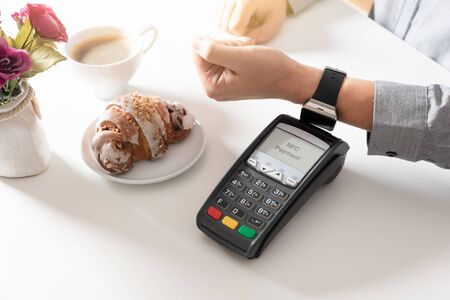Man using smart watch to pay in restaurant. NFC contactless convenient payment serviceの写真素材