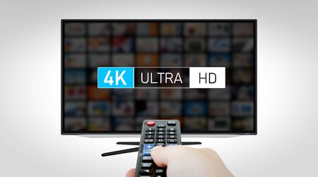 4K high resolution television. TV multimedia concept. Hand with remote controlの写真素材