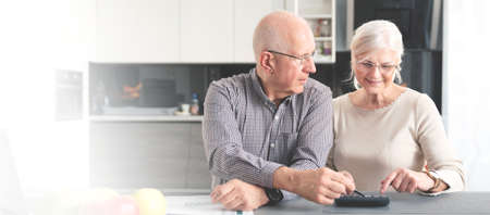 Senior couple calculating budget together. Retirees pay the bills. Web banner image background with copy space.の写真素材