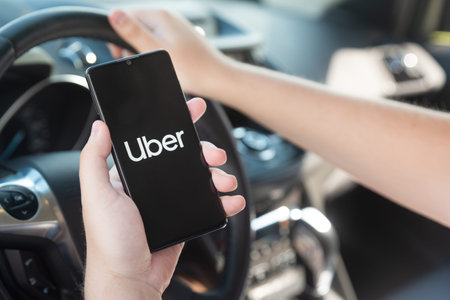 Wroclaw, Poland - AUG 25, 2020: Uber driver holding smartphone in car. Uber is sharing-economy...