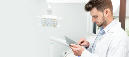 Doctor with tablet in dentist office. Telemedicine, remote health care concept. Web banner with copy...