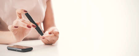 Woman taking blood sample with lancet pen. Diabetes, health care concept. Image background with copy spaceの写真素材