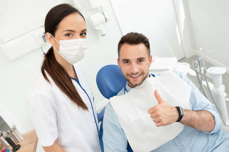 Young doctor dentist and patient showing thumb up. Healthy teeth concept.の写真素材