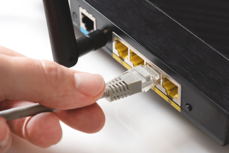 router close up. Fast internet modem device. Man plugs  cable into socketの写真素材