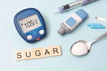 Treatment and controlling diabetes concept. Glucometer, spoon with sugar.の写真素材