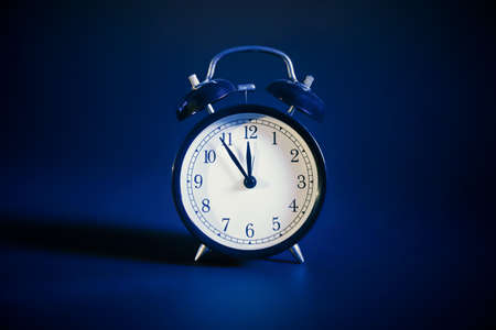 Analog clock front view, dark blue backgroundの写真素材