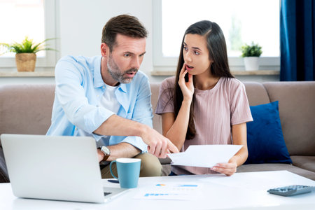 Young couple calculating money at home. Financial revision, home budget concept