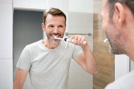 Man brushing his teeth in the bathroom. White teeth and a beautiful smile, morning hygiene conceptの写真素材