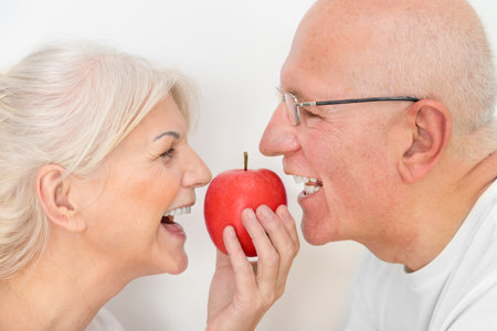 Two elderly people holding an apple. Healthy and strong teeth conceptの写真素材