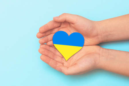 Hand holding a heart with Ukrainian national colors. Help Ukraine during the warの写真素材