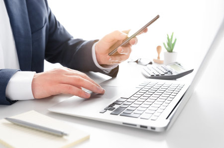 Businessman working in the office. Accountant or bookkeeper working with laptop and smartphone.