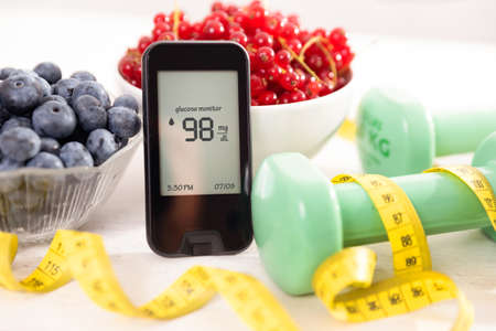 Glucometer with sugar level, diabetes concept. Fresh druits in bowl, diet and nutrition.の写真素材