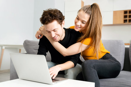 Young couple enjoying internet time, looking in laptop