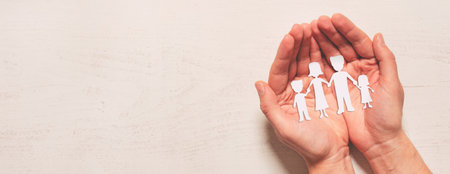 Family care concept. Hands with paper family silhouette on table.の写真素材