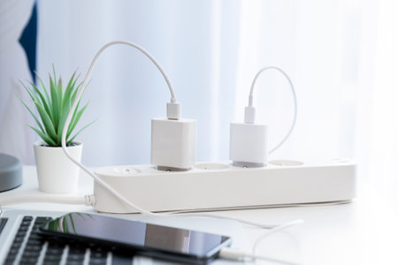 Charger connected to a power white strip on deskの写真素材