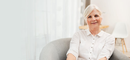 Happy senior woman in living room. Looks beautiful in retirementの写真素材
