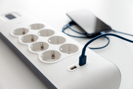 Smartphone charging at home. Electrical equipment, electrical wires and power strips in the houseの写真素材