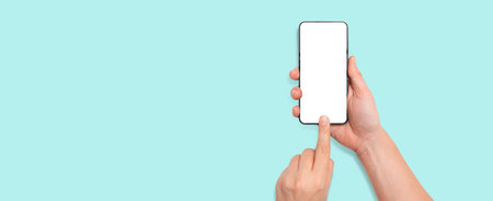 Hand holding modern smartphone, isolated mockup on blue backgroundの写真素材
