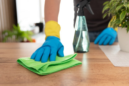 Maintaining the house, cleaning services. Person is cleaning a table with a green cloth.の写真素材