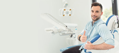 Patient in dentist office, showing thumb up, dental care concept, copy space imageの写真素材
