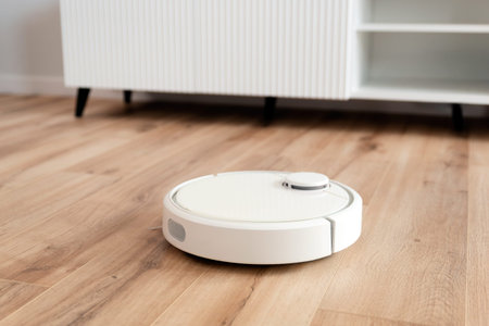 White robot vacuum cleaner on the floor in the living room, smart home device