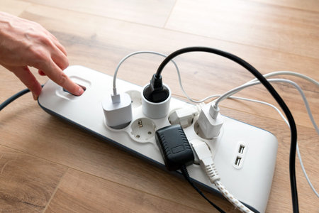 Person is plugging in a device to a power strip. Man holding phone charger.
