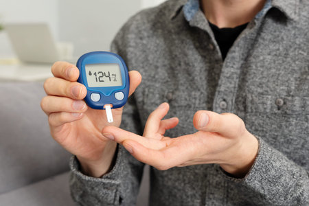 Young man measures blood sugar level. Diabetes using glucometer.