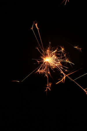 Yellow sparks fly on a black background, layered with grain, noise, and glowing effects to give a...